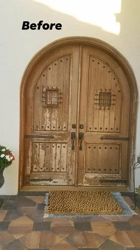 Arched solid wood double entry doors before refinishing, with sun-bleached and peeling finish