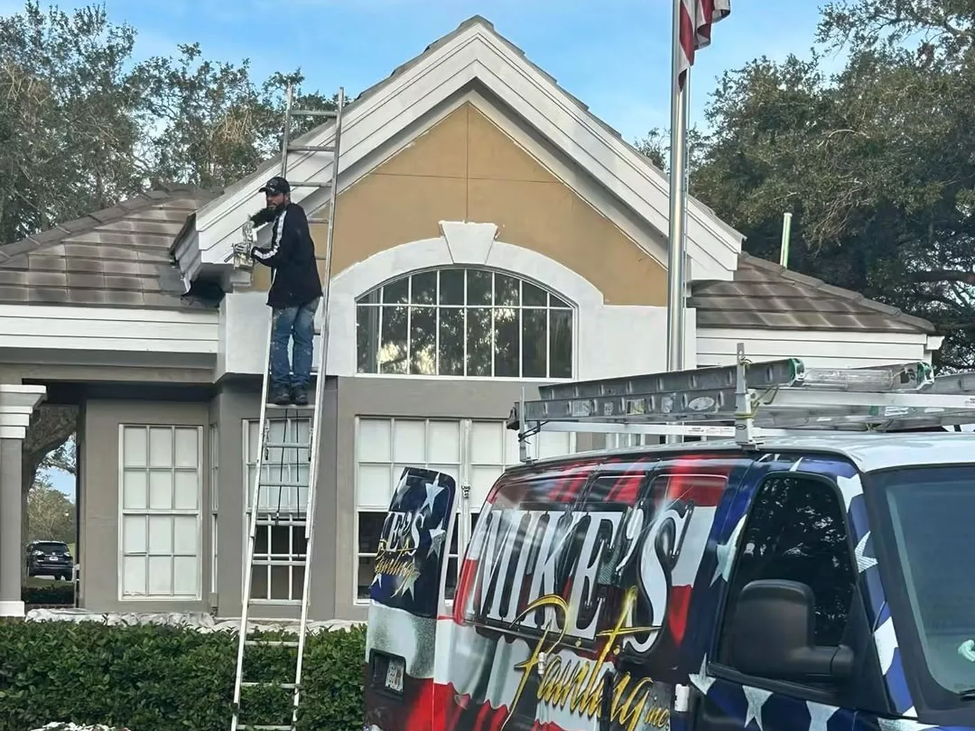 Mike's Painting crew repairing fascia and soffit on a Lakeland clubhouse from a ladder