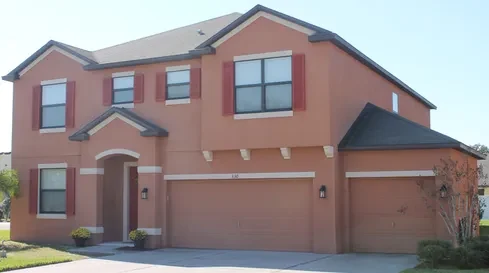 Large two-story home painted in terracotta with deep red shutters and a three-car garage